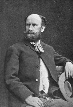 Photograph of a bearded man in a dark coat and light waistcoat