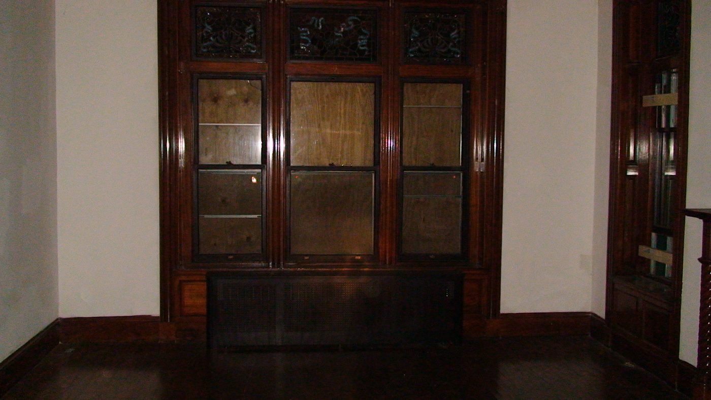 A boarded window bay inside the empty house