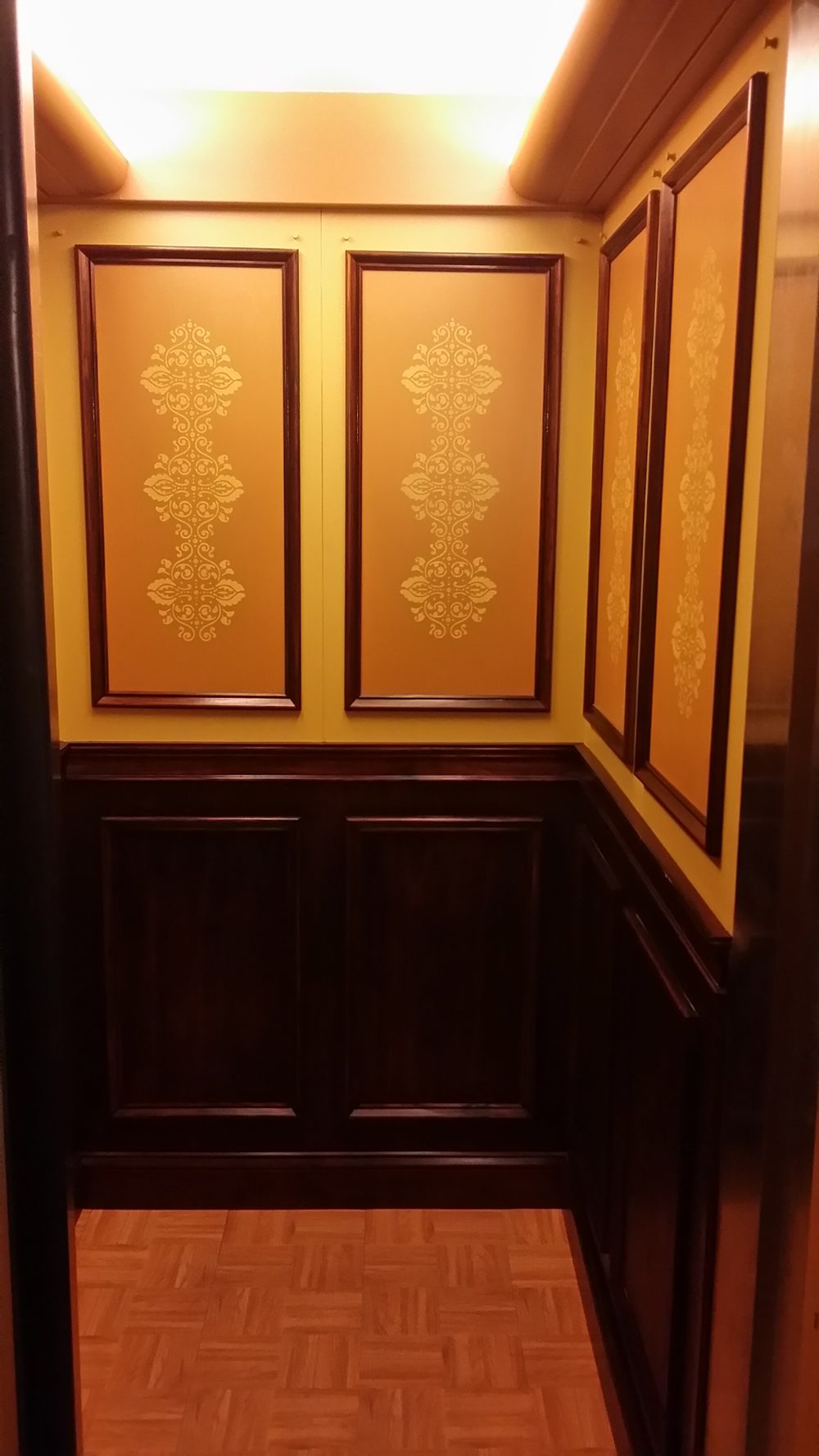 Inside the small wood-panelled elevator cab