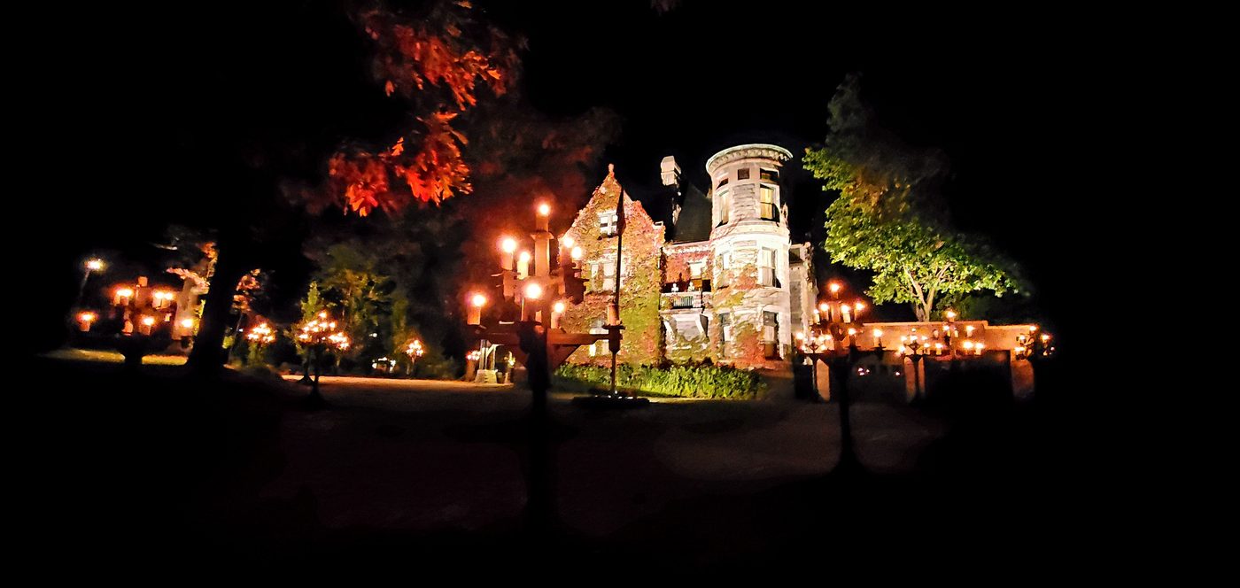The castle lit orange at night, candelabras in the foreground