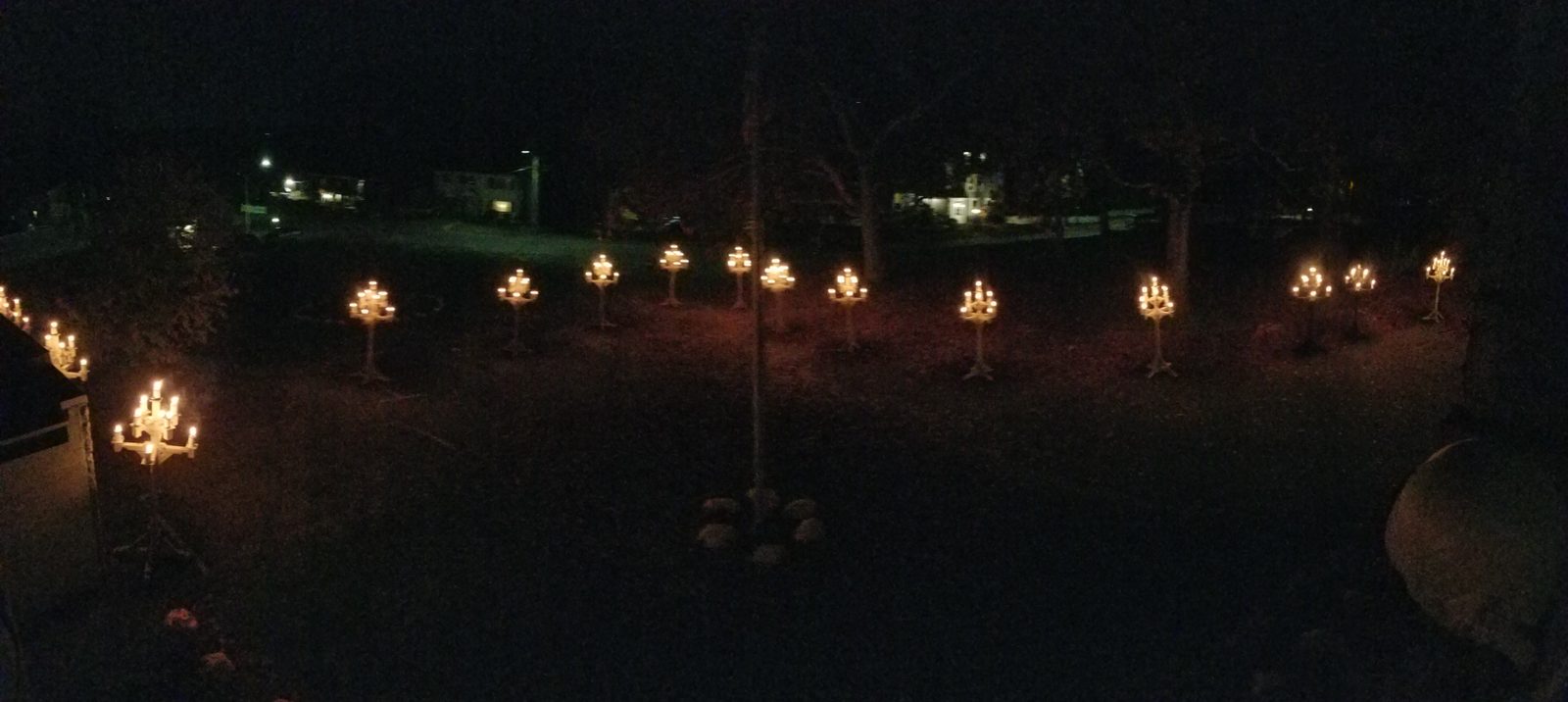 Panorama of candelabras across the dark lawn