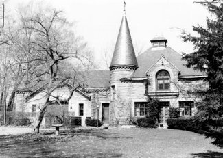 Black-and-white 1981 survey photograph of the former stable, a stone house with a conical-roofed round tower among trees