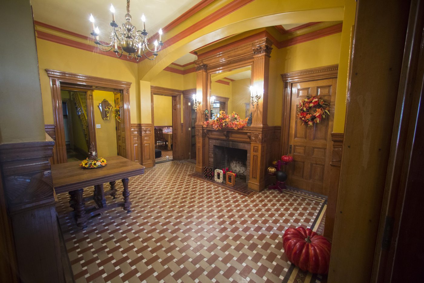 The grand entry hall: oak panelling, a carved fireplace and a patterned tile floor