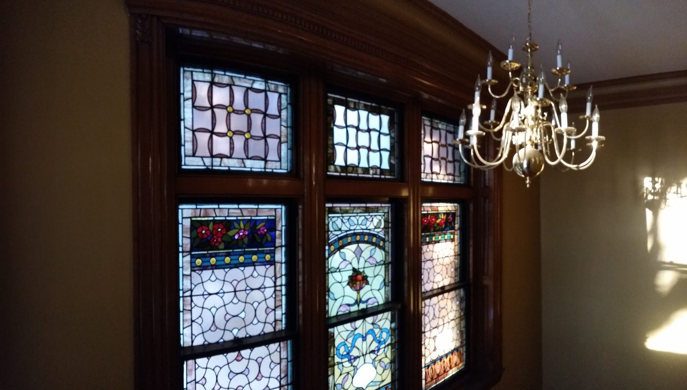 Three stained-glass windows with a chandelier beside them