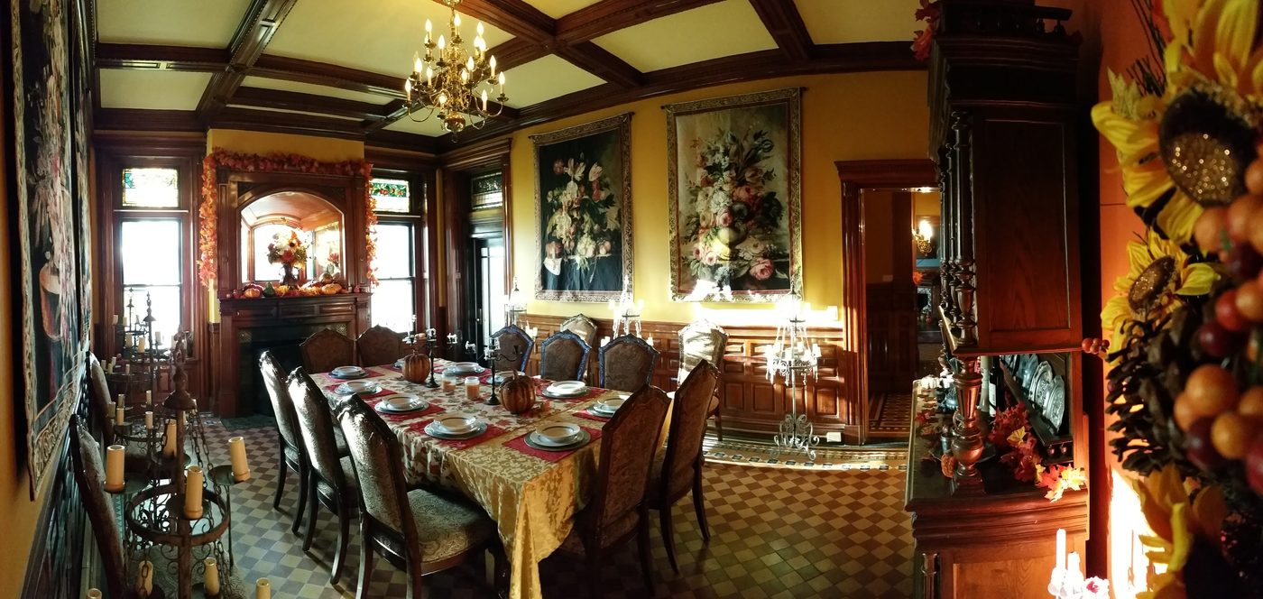 The dining room set for dinner under a coffered ceiling