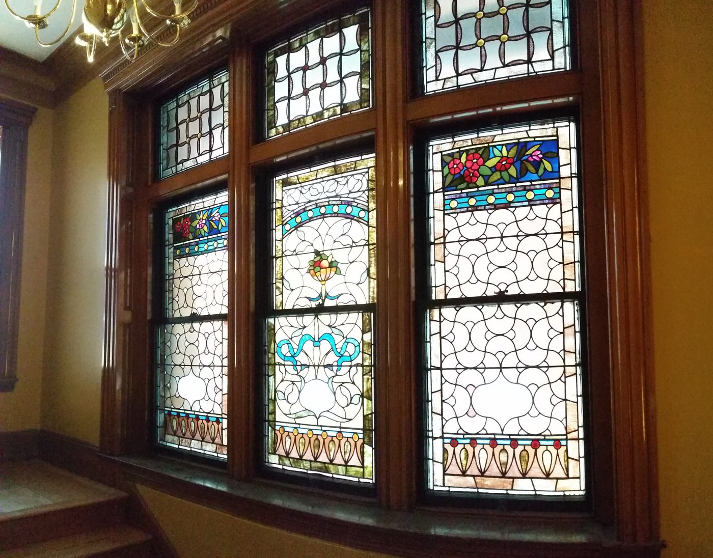 A bay of three stained-glass windows with a patterned border