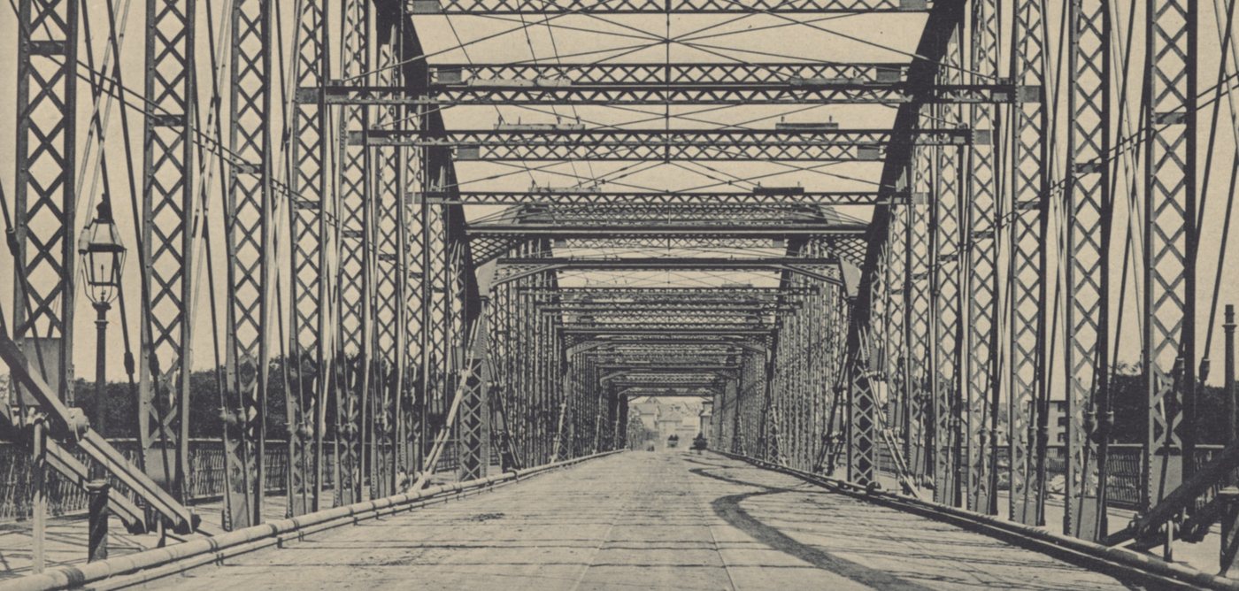 Looking through the steel trusses of a long bridge along its roadway