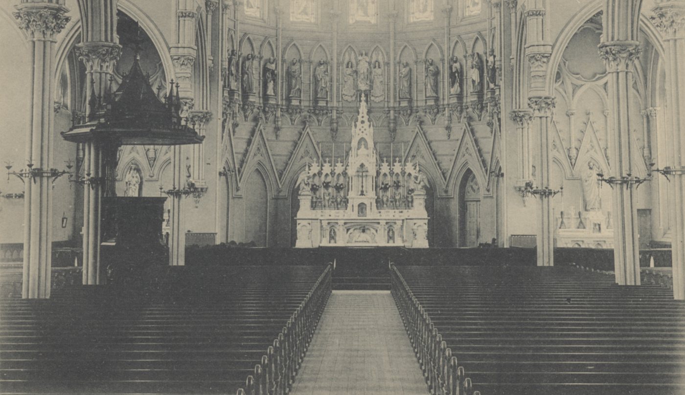 The interior of a large church looking up the aisle to a carved altar and Gothic arches