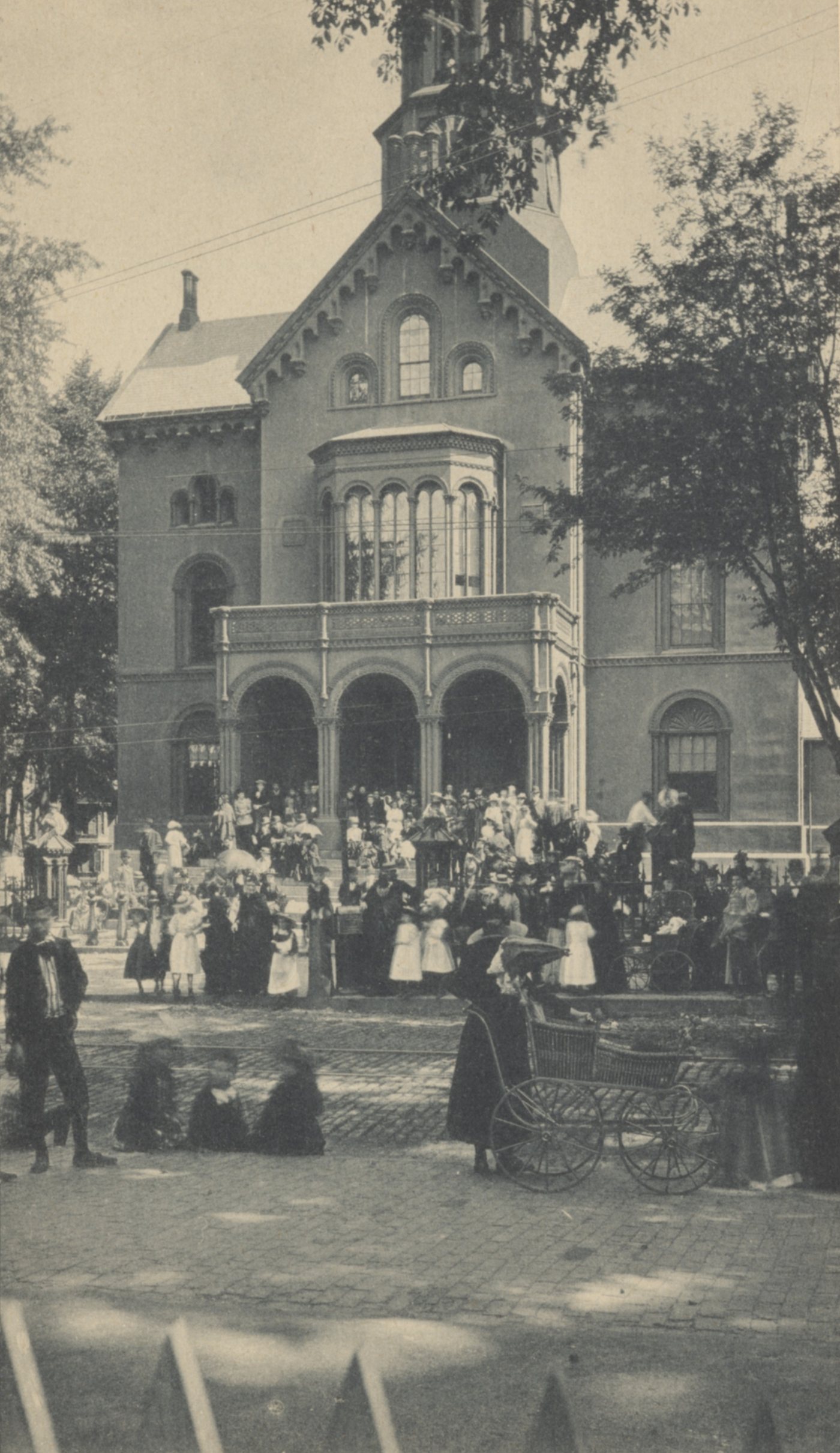 A large crowd gathered in front of an arched brick courthouse