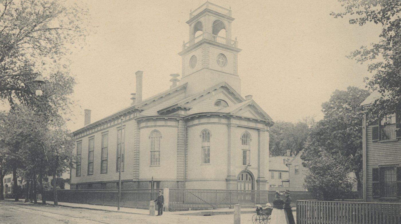 A white church with a bell tower, among trees