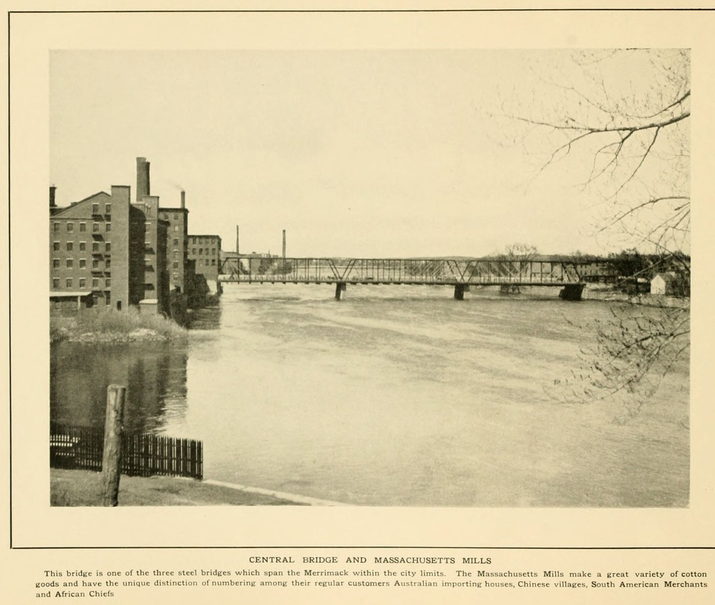 A steel truss bridge across the river with brick mill buildings on the far bank