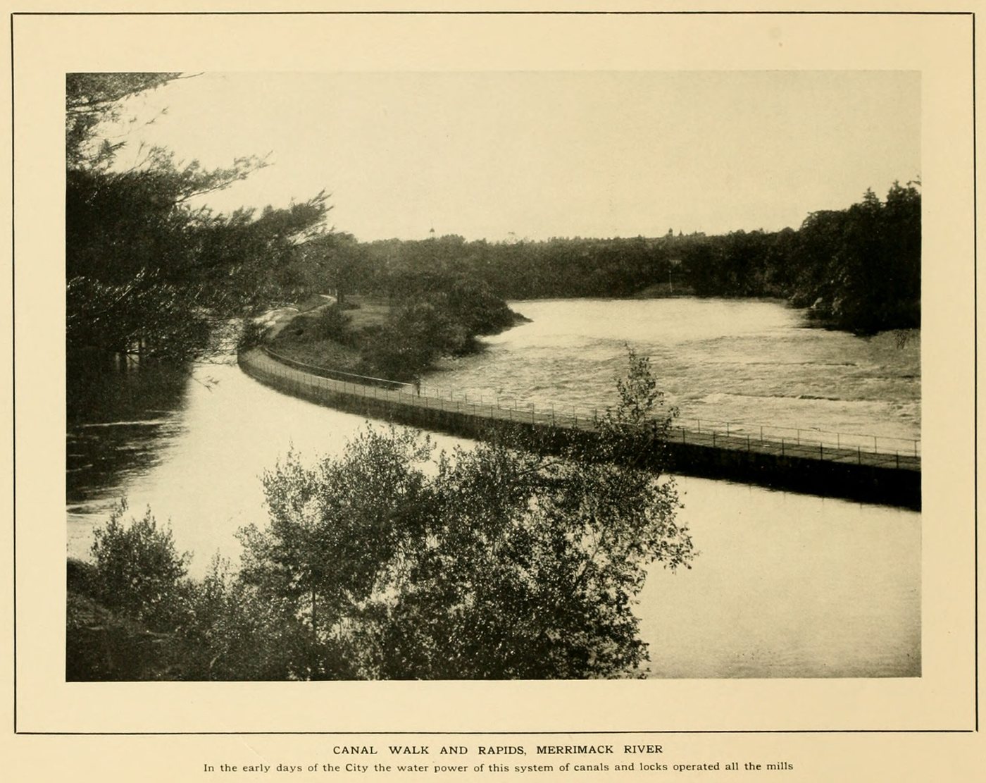 A curving canal wall and walk beside rapids in the river, with trees in the foreground