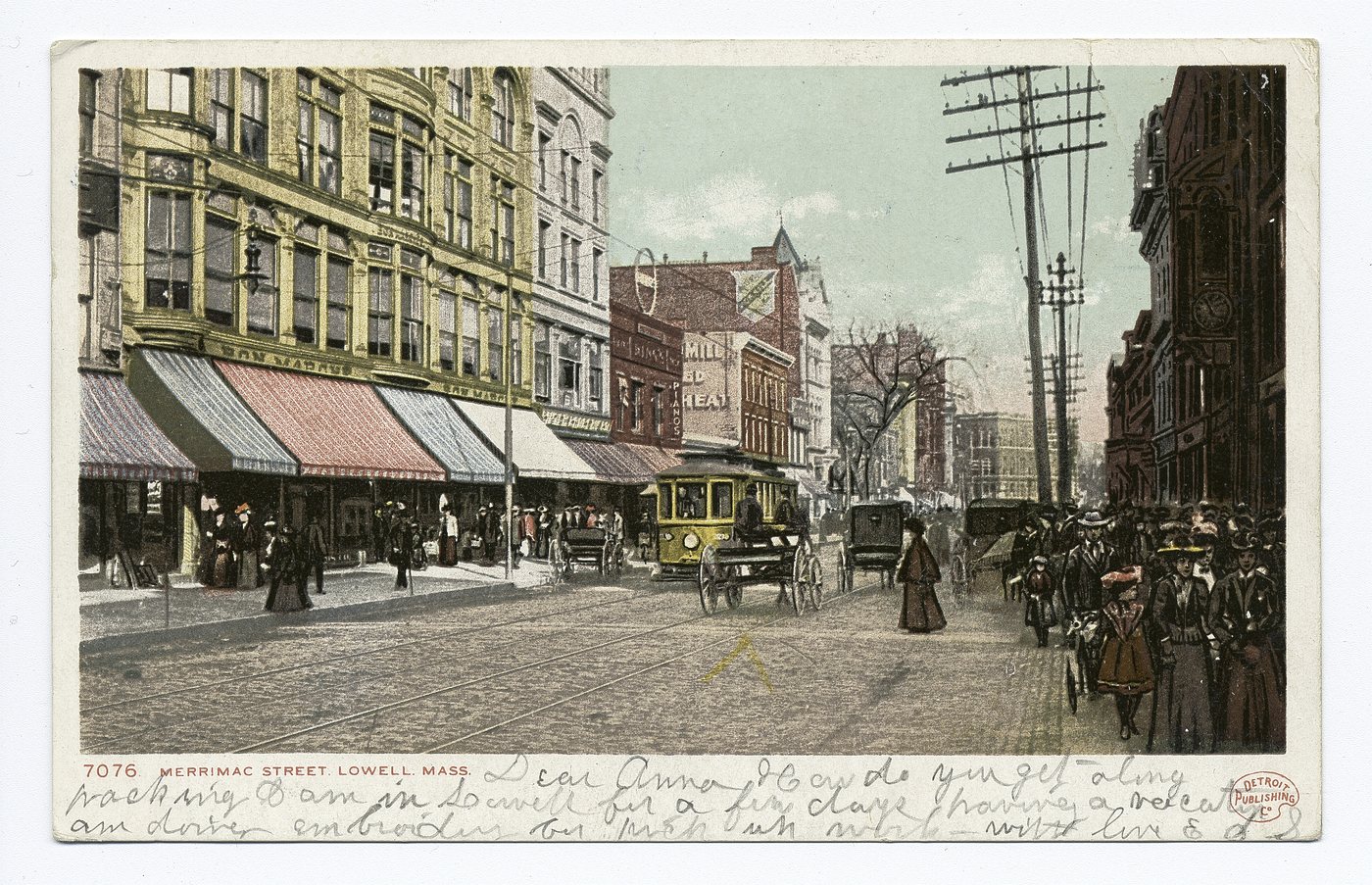 A color postcard of a busy shopping street with awnings, a streetcar, carriages and shoppers