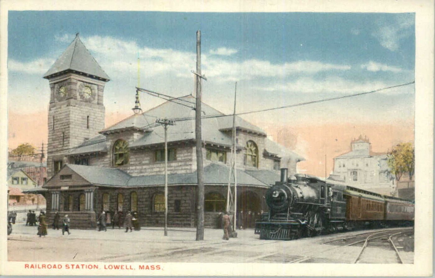 A color postcard of a steam locomotive and passenger cars beside a depot with a clock tower