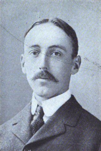 Black-and-white halftone portrait of a young man with a mustache and center-parted hair, in a dark coat and white collar