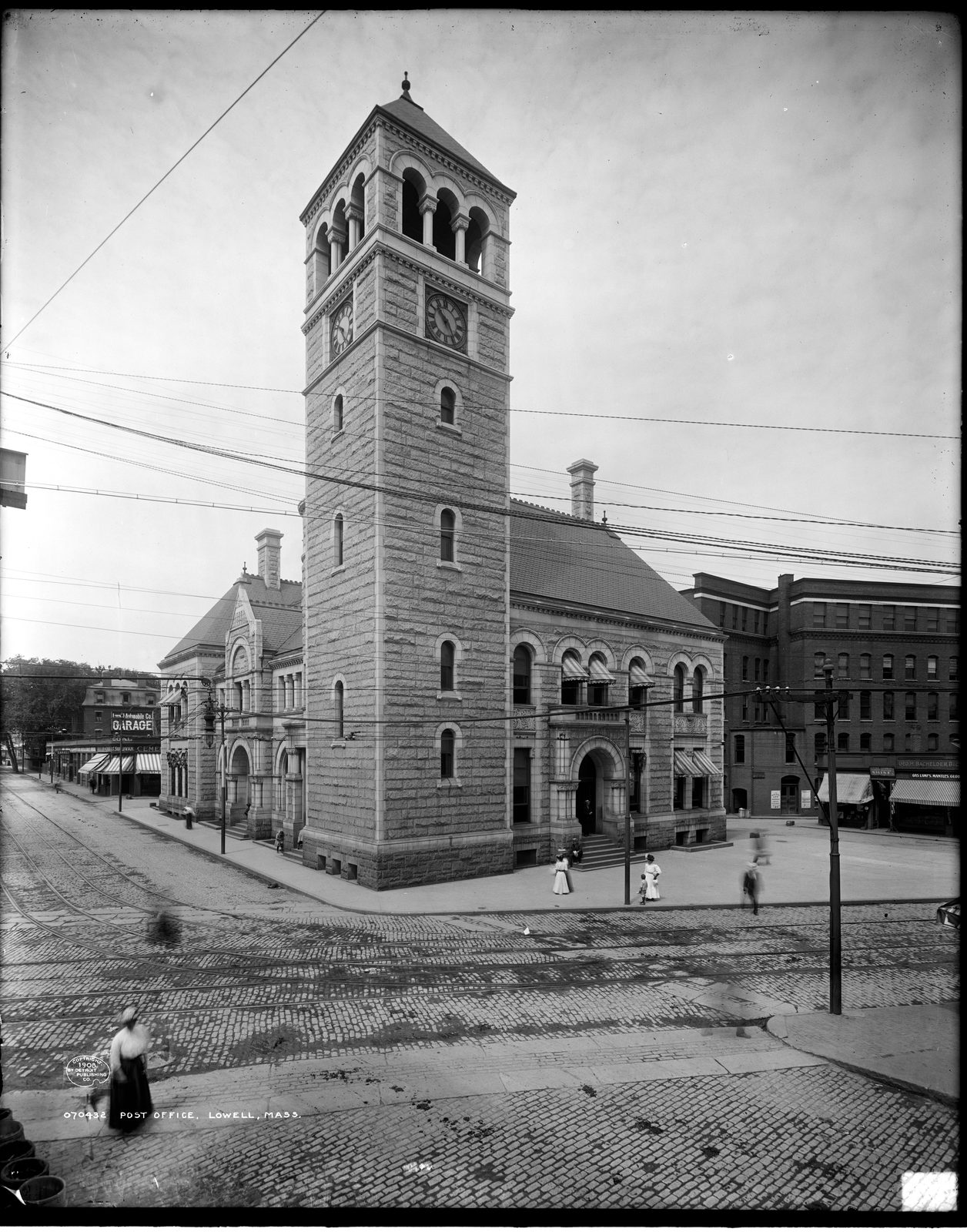 The Lowell Post Office about 1908: a granite building with a tall square tower with arched openings and a round-arched entrance
